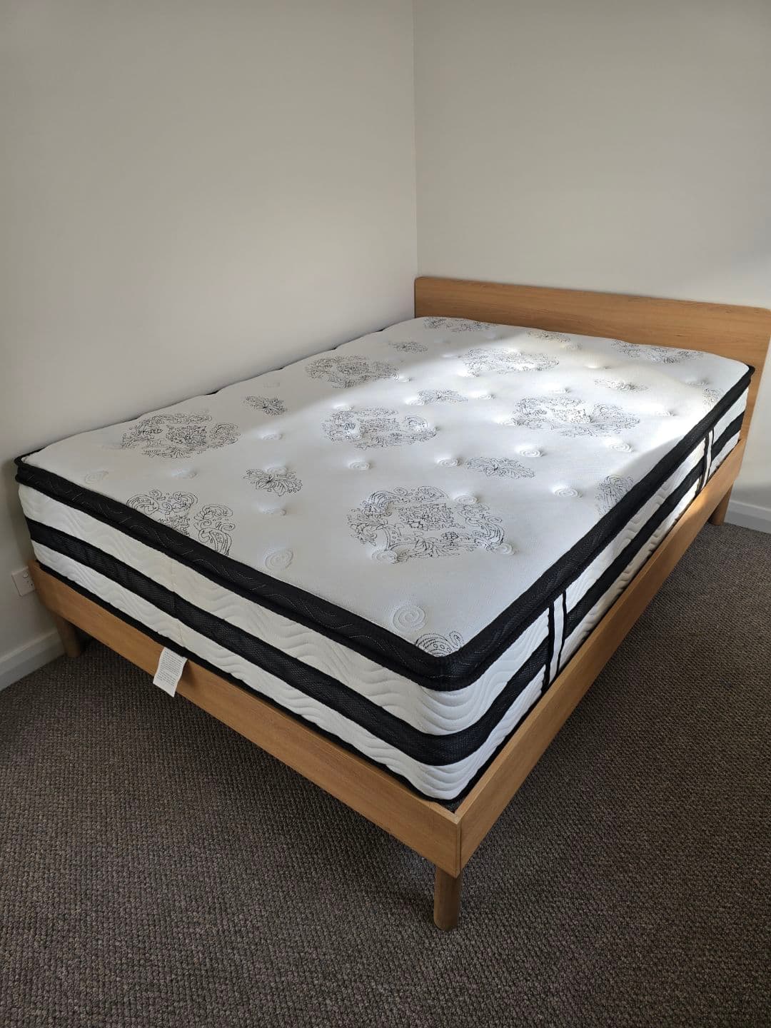 Assembled timber bed frame with mattress in a bedroom