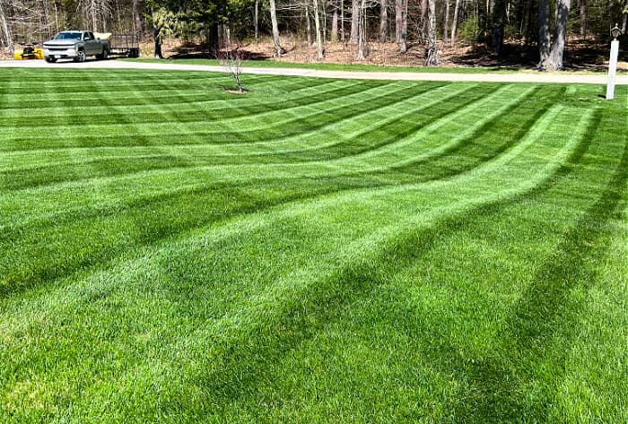 Mower cutting a striped green lawn