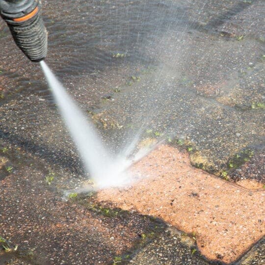 Pressure washer cleaning a paved surface